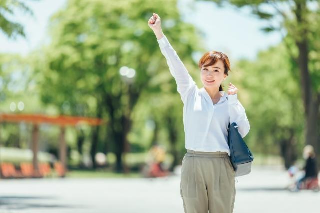 緑に囲まれた公園で手をあげる女性